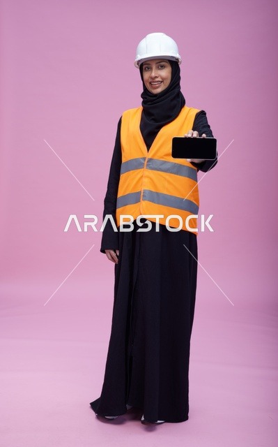 مهندسة سعودية تمسك هاتف ذكي بخلفية وردية