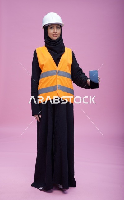 مهندسة سعودية تحمل هاتف ذكي بخلفية وردية
