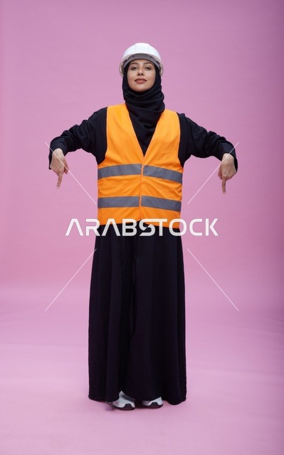 مهندسة سعودية بملابس السلامة تشير لأسفل