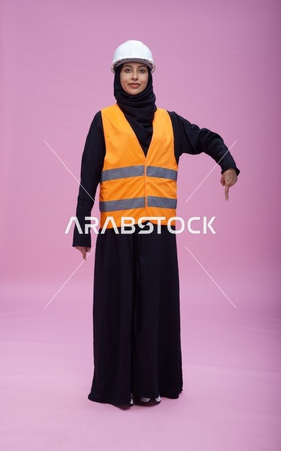 مهندسة سعودية بملابس السلامة تشير إلى الأسفل