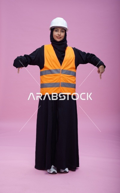 مهندسة سعودية بملابس السلامة والخوذة تشير للأسفل
