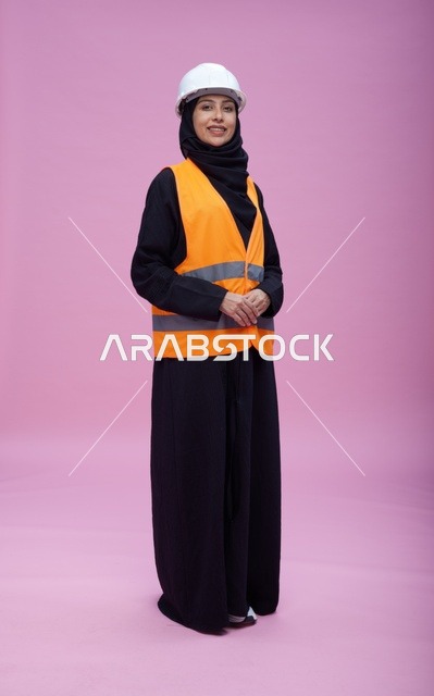 مهندسة سعودية بملابس السلامة والخوذة أمام خلفية وردية