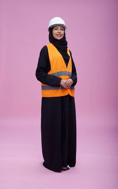مهندسة سعودية بملابس السلامة والخوذة أمام خلفية وردية