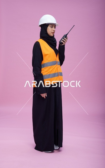 مهندسة سعودية بجهاز لاسلكي أمام خلفية وردية