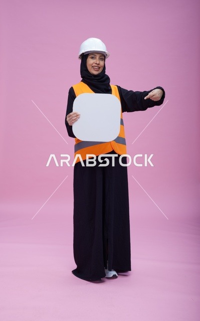 مهندسة سعودية تحمل لوحة بيضاء فارغة بخلفية وردية