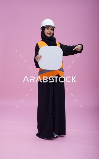 مهندسة سعودية تحمل لوحة بيضاء فارغة بخلفية وردية