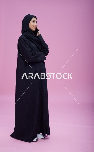 امرأة سعودية تتحدث بالجوال أمام خلفية وردية