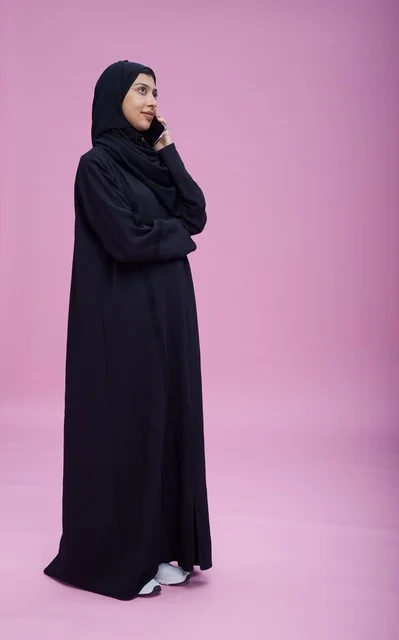 امرأة سعودية تتحدث بالجوال أمام خلفية وردية