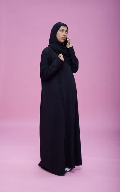 Saudi Woman in Abaya Talking on Smartphone Pink Background