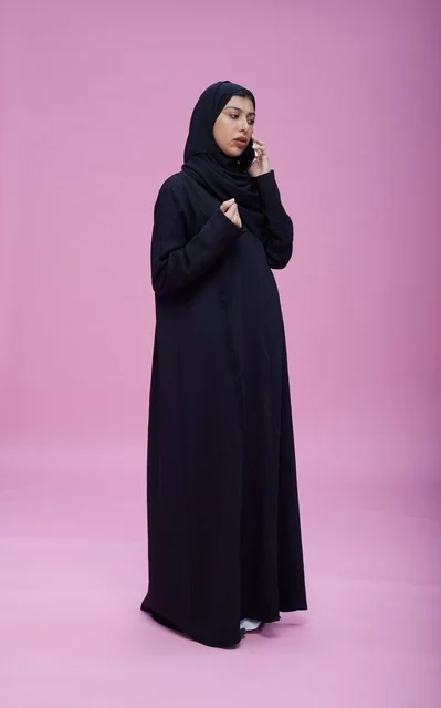 Saudi Woman in Abaya Talking on Smartphone Pink Background