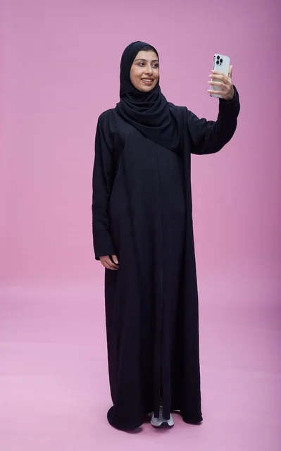 امرأة سعودية بالعباءة تلتقط سيلفي خلفية وردية