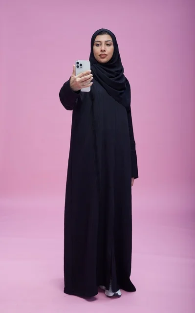 Saudi Woman Taking Selfie on Smartphone with Pink Background