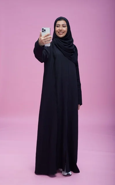 Saudi Woman in Black Abaya Taking Selfie on Pink Background