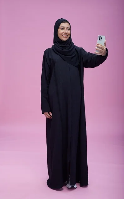 Saudi Woman in Abaya Taking Selfie on Pink Background