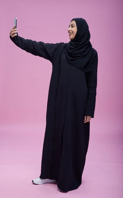 Saudi Woman in Abaya Taking Selfie on Pink Background