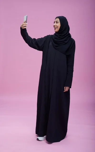 Saudi Woman in Black Abaya Taking Selfie on Pink Background