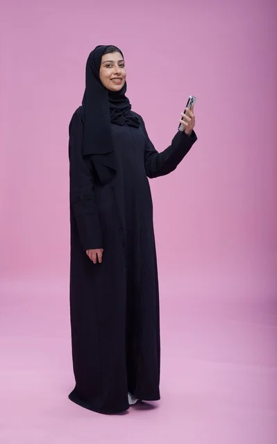 امرأة سعودية بالعباءة تلتقط سيلفي على خلفية وردية