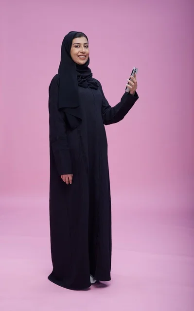 امرأة سعودية بالعباية تلتقط سيلفي على خلفية وردية
