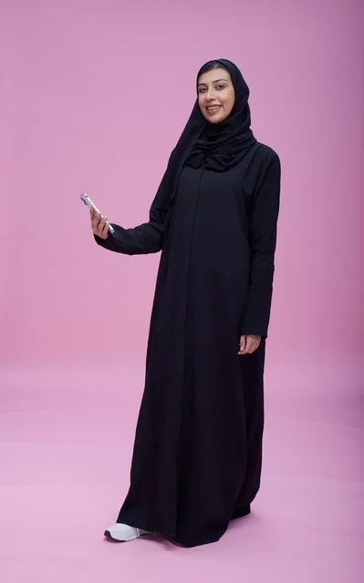 امرأة سعودية بالعباءة تلتقط سيلفي خلفية وردية