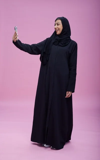 Saudi Woman in Abaya Taking Selfie on Pink Background