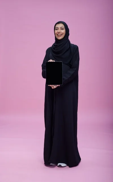 امرأة سعودية تحمل جهازاً لوحياً بشاشة فارغة