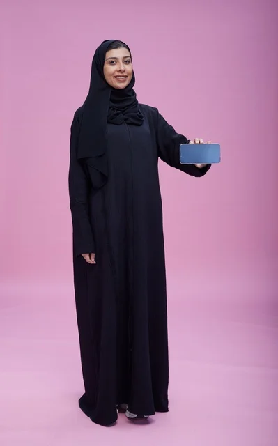 Saudi woman in abaya holding smartphone with blank screen