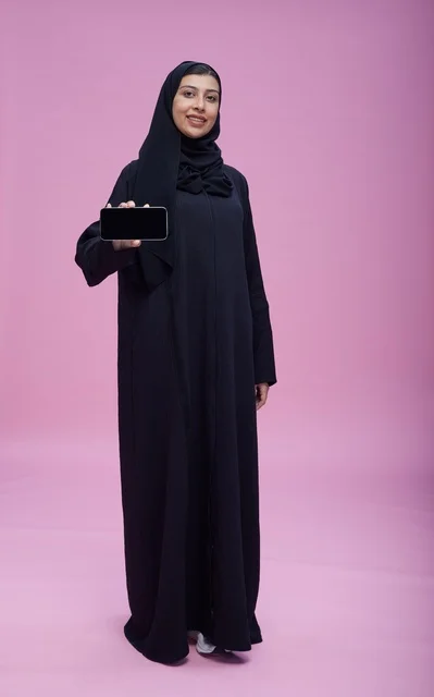 امرأة سعودية بالعباءة تحمل هاتف بشاشة فارغة