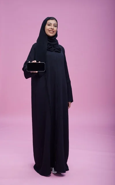 امرأة سعودية بالعباءة تحمل هاتفاً ذكياً بشاشة فارغة