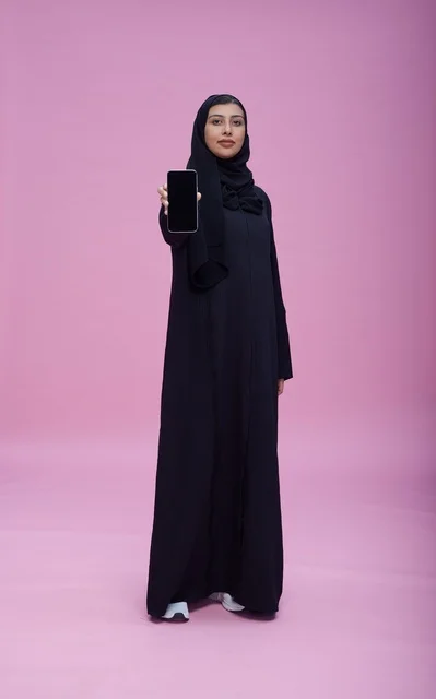 امرأة سعودية بالعباءة تحمل هاتف بشاشة فارغة