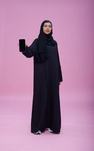 امرأة سعودية بالعباءة تحمل هاتف بشاشة فارغة