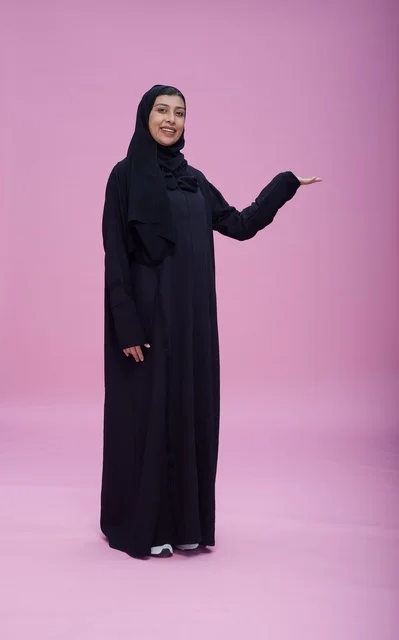 Saudi Woman in Abaya Presenting on Pink Studio Background