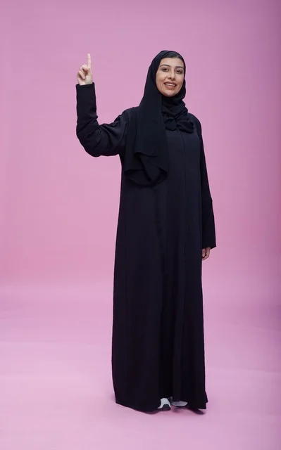 Saudi Woman in Abaya Pointing Up on Pink Background