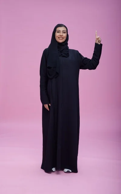 Saudi Woman in Abaya Pointing Upward on Pink Background