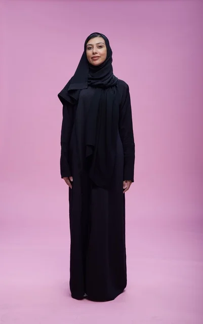 امرأة سعودية بالعباءة السوداء في استوديو بخلفية بنفسجية