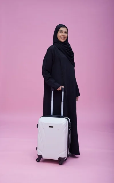 Saudi Woman in Abaya with Suitcase on Pink Background