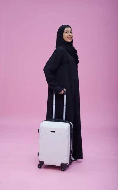 امرأة سعودية بالعباءة مع حقيبة سفر بيضاء
