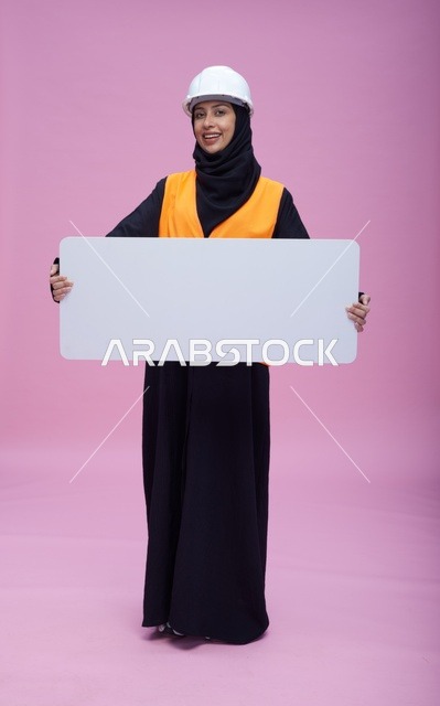 مهندسة سعودية ترتدي خوذة سلامة وتحمل لوحة بيضاء فارغة