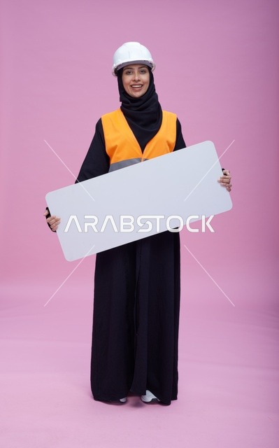 مهندسة سعودية تحمل لوحة عرض فارغة خلفية وردية