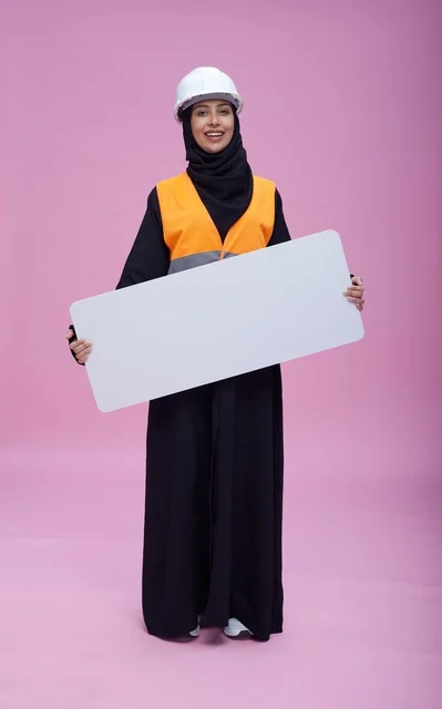 مهندسة سعودية تمسك بلوحة عرض فارغة بخلفية وردية