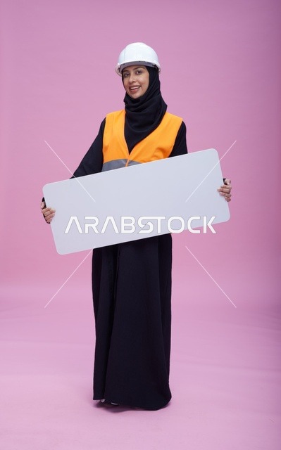 مهندسة سعودية تحمل لوحة عرض فارغة خلفية وردية