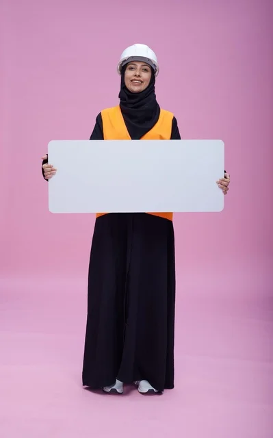 مهندسة سعودية تحمل لوحة عرض بيضاء فارغة بخلفية وردية
