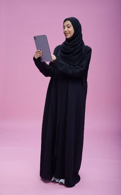 Saudi Woman Using Tablet in Studio Pink Background