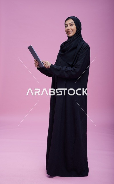 Saudi Woman Using Tablet on Pink Studio Background