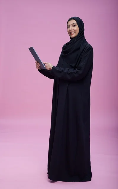 Saudi Woman Using Tablet on Pink Studio Background