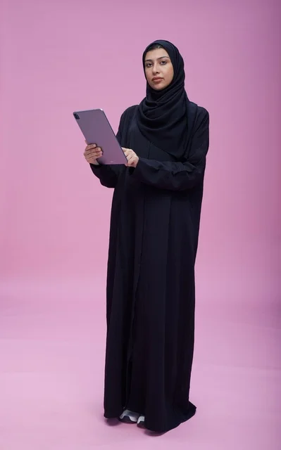 Saudi Woman in Abaya Using Tablet in Pink Studio