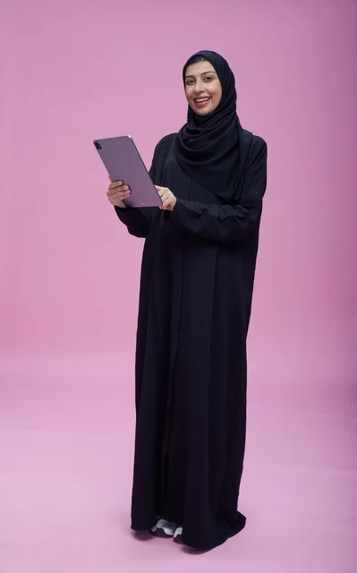 Saudi Woman with Tablet on Pink Studio Background