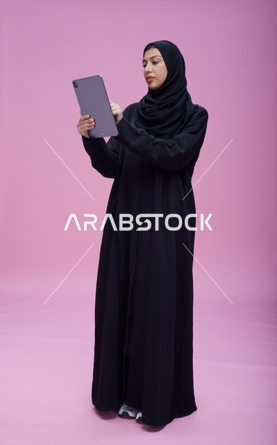 Saudi Woman Using Tablet on Pink Studio Background