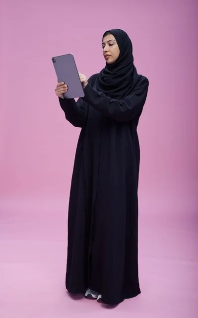 Saudi Woman Using Tablet on Pink Studio Background
