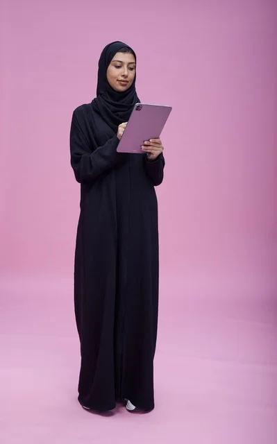 Saudi Woman Using Digital Tablet on Pink Studio Background