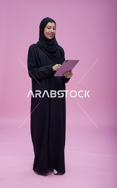 Saudi Woman Using Tablet on Pink Background